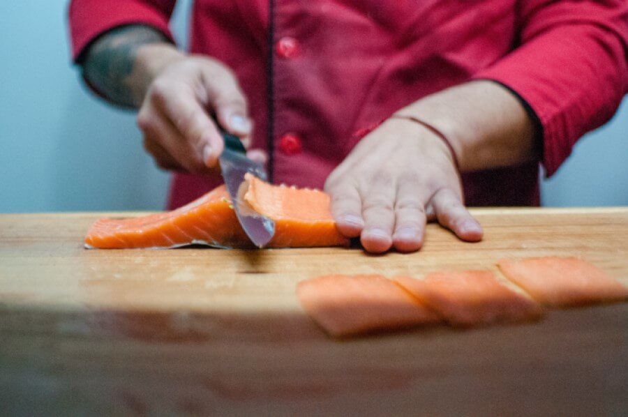 person slicing salmon with knife