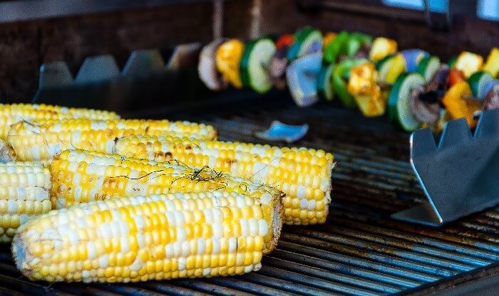 upclose view of grill with corn and vegetable skewers